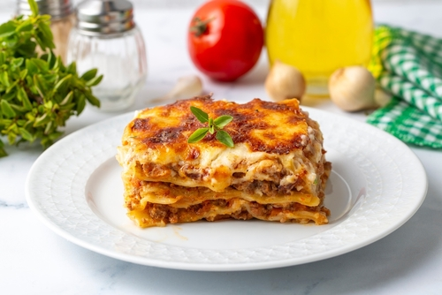 Na imagem, há um pedaço de lasanha de carne moída com queijo parmigiano reggiano