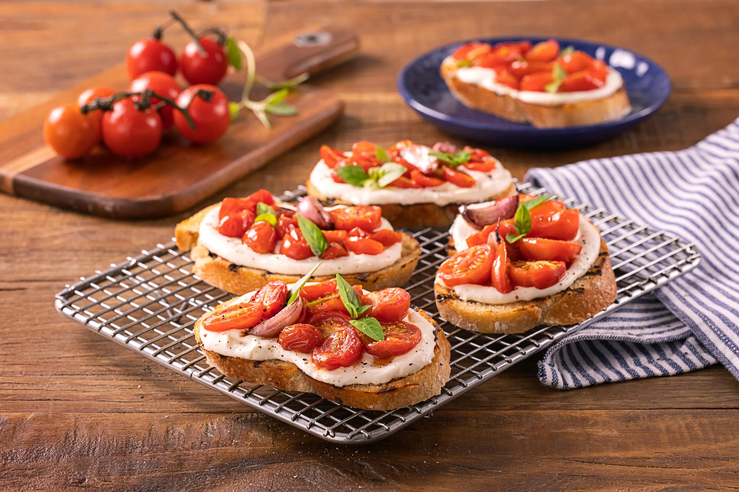 Na imagem, há cinco brischettas italianas de pães com tomate e folhas de manjericão