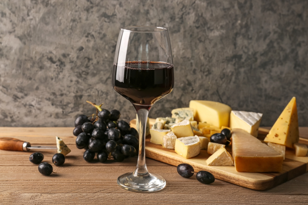 Tábua de queijos ao lado de duas taças de vinho