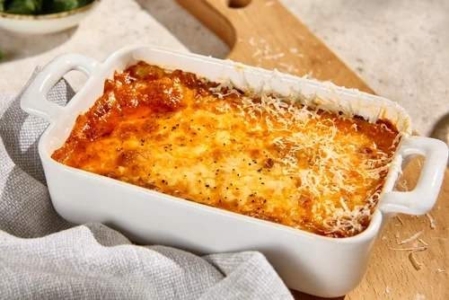 Na imagem, há uma travessa com lasanha de bacalhau gratinada com queijo mussarela