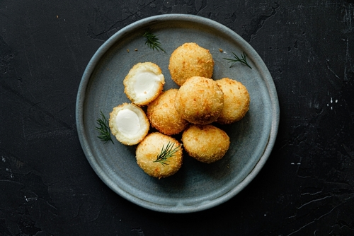 Na imagem, há um prato com uma porção de bolinhas de queijo